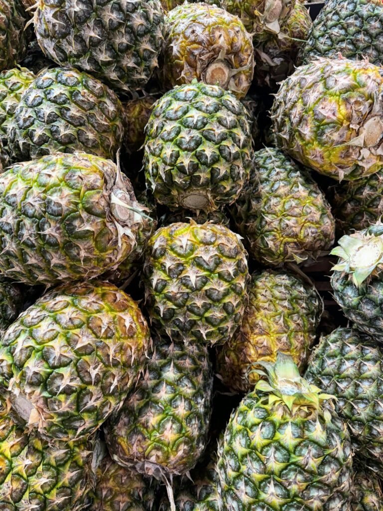 A vibrant collection of fresh pineapples at a market stall, showcasing their natural textures and colors.